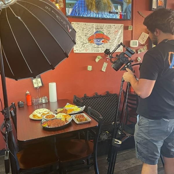 A person filming various dishes on a table with professional lighting in a restaurant.